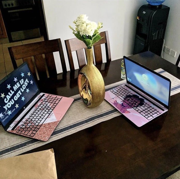Two custom laptop skins with full keyboard coverage on a dining table